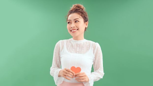 Beautiful young woman with red heart on color background