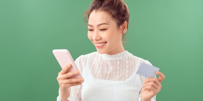 Smiling girl holding phone and credit card. Shopping online concept.