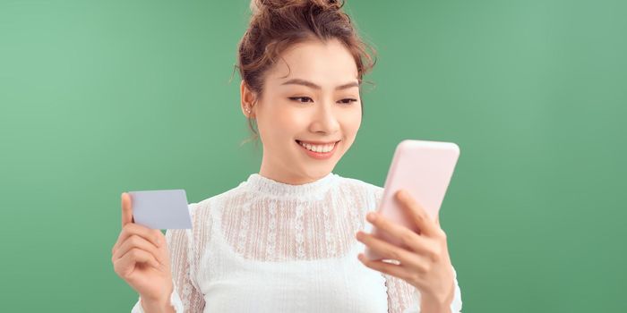 Happy young woman using mobile phone and credit card.