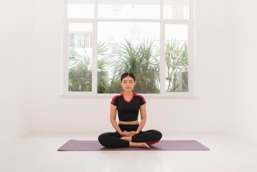 A woman practices yoga near the window
