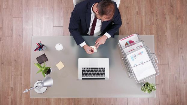 Top view of businessman talking at phone with partner writing corporate profit on stickey notes while working in startup business office. Sccessful director brainstorming management strategy ideas