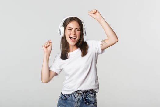 Attractive joyful girl dancing in wireless headphones, listening music.