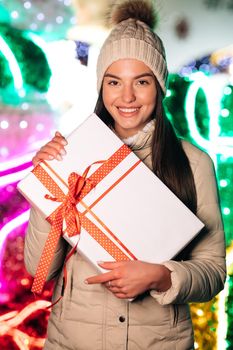 Portrait young pretty woman with christmas present. Happy young woman in hat holding christmas present box