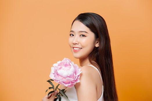 beautiful young woman with pink flower isolated on yellow