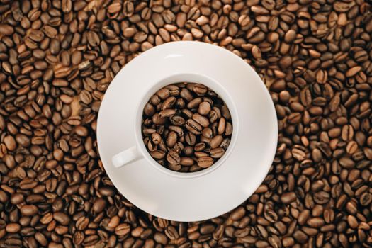 Close-up of coffee cup with roasted coffee beans on wooden background. View from top