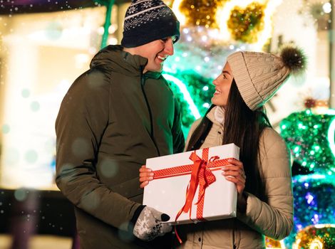 Gift Box. Boyfriend Making Holiday Surprise to His Woman Celebrating Together Giving Christmas Present. Happy Couple Stand Hugging Outdoors.