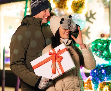 Boyfriend Making Holiday Surprise to His Woman Celebrating Together Giving Christmas Present. Lovely Couple Stand. Gift Box Hugging Outdoors.