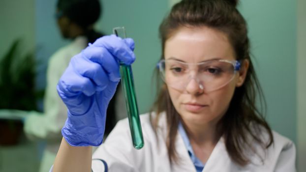 Chemist researcher woman holding test tube with dna liquid observing genetic mutation on sample researching for biochemistry expertise. Scientist biologist working in agriculture laboratory