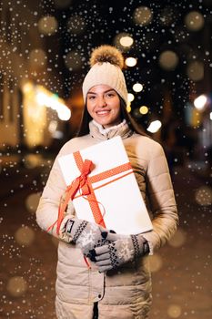 Happy woman with present on christmas gift box. Girl in hat looking camera. Christmas present. Merry Christmas or Happy New Year 2021. Person holding the box to the birthday