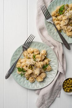 radiatori pasta with cherry tomatoes, cheese and parsley in white plate on wooden background, top view copy space
