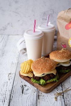 Fat unhealthy food close-up. Set of homemade burgers, chips and drink