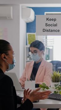 Coworkers wearing medical face masks to prevent infection with coronavirus while working in office company. Business woman talking with her team during online communication meeting
