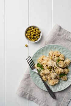 radiatori pasta with cherry tomatoes, cheese and parsley in white plate on wooden background, top view copy space