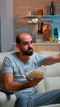 Caucasian football fan watching his team winning the competition, eating popcorn. Match goal in living room late at night, cheerful scoring win celebrating championship