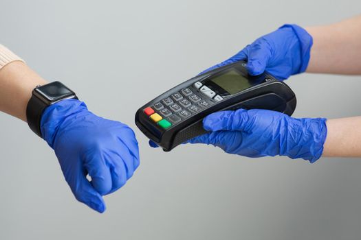 Woman's hand in gloves using smartwatch to purchase product at the point of sale terminal nfc identification payment technology use for verification