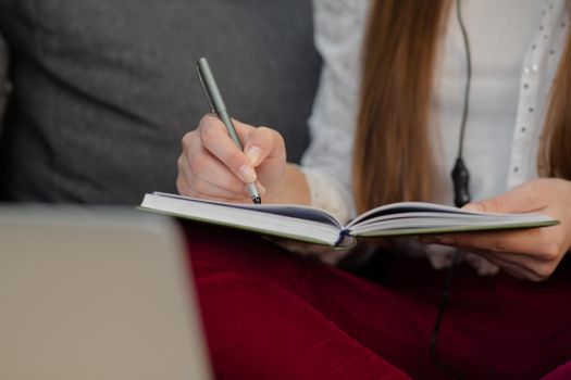 Smiling teen girl wearing headphones listening to audio course making notes, young woman learning foreign languages, digital self education, studying online, enjoying music