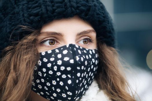 Portrait of a young tourist woman wearing protective face mask on street crowd people. Health and safety, N1H1 coronavirus quarantine, second wave covid virus. Vacation winter outdoor curly girl.