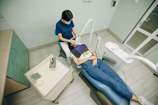 Dentist doing teeth whitening procedure with ultraviolet lamp. Concept of teeth care and dentistry. Led teeth whitening. Ultraviolet rays. Lamp for teeth enamel whitening. Beautiful smile