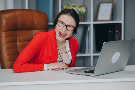 Happy woman wear headset communicating by conference call speak looking at camera at home office. Video chat job interview or distance language course class with online teacher concept.