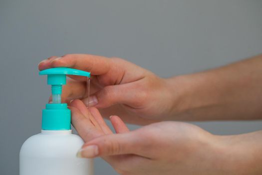 Woman Hands using wash hand sanitizer gel pump dispenser. Clear sanitizer in pump bottle, for killing germs, bacteria and virus.