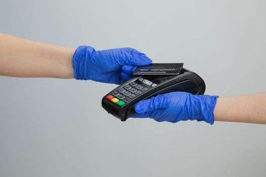 Woman hand in gloves with credit card swipe through pos terminal and enter pin code. Banking services of electronic money. Financial success and safety. Credit card machine for money transaction.