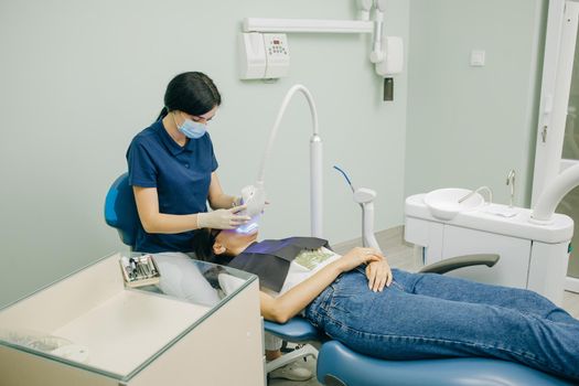 Dentist stomatologist whitening teeth for patient in medicine dental clinic with lamp. Concept of teeth care and dentistry. Teeth whitening procedure.