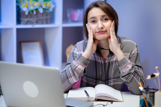 Cute girl looking and overwhelmed sitting at the desk at home doing homework. Stress emotions surprised expressive studying learning home.