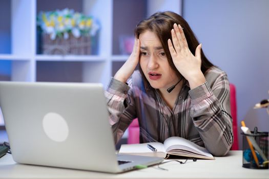 Modern online education, communication and technology concept. Shocked girl with laptop at home. Cute girl doing homework on computer.