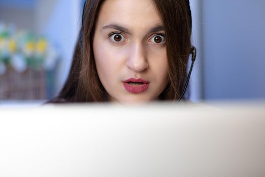 Surprised girl with laptop at home. Cute girl doing homework on computer. Modern online education, communication and technology concept