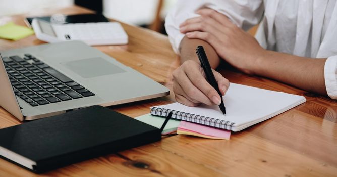Female accounting or bookkeeper providing accounting service for small businesses, holding pen to make notes and using calculator, woman using digital tablet and calculator.