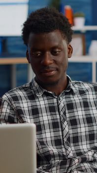 Young interracial couple chatting on video call conference in living room. Multi ethnic people talking on laptop camera for remote communication while sitting at home on couch.