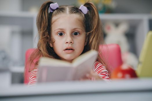 Little girl reading book indoor.