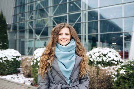 Portrait of beautiful stylish caucasian woman smiling at camera looking confident. Wearing blue scarf, urban city background. Real people. Beautiful charming girl enjoying fashion.