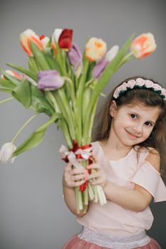 Women's Day. Attractive girl holding a bouquet of tulips in her hands. Smile, joy, happiness, beauty.