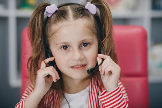 Portrait of smiling little girl wearing headphones. Happy small preschooler child in earphones have fun. Studying online on quarantine