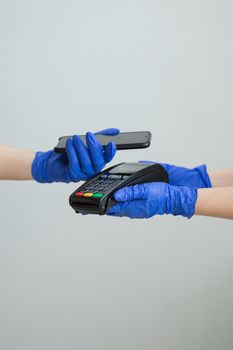 Nfc cellhone of female buyer with cashless wallet of e-money for pos card reader and checkout. Woman in gloves applies smartphone to terminal performing successful contactless payment.