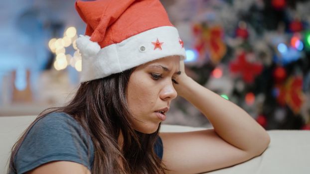 Close up of person playing video games on console and losing with joystick. Angry woman with play and controller wearing santa hat and celebrating christmas eve holiday. Adult with internet