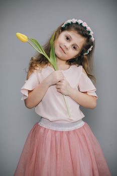 Portrait of a little girl with a bouquet of spring flowers on background. Child holding a tulip in his hand. Spring concept