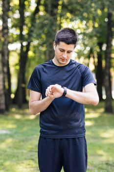 Sport man looking smart watch. Man runner using smart watch. Handsome guy tracking result after workout. Portrait of fitness man checking result.
