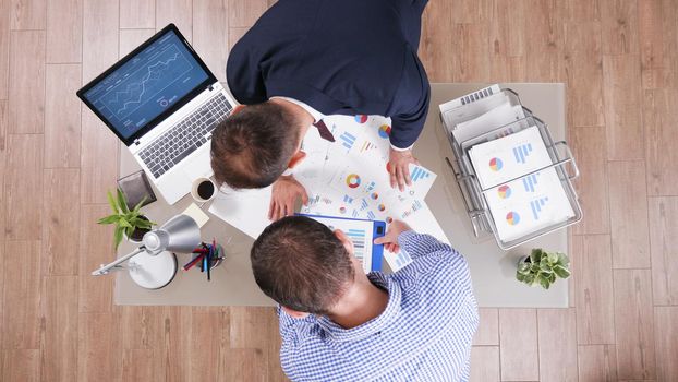 Top view of businessmen working at company strategy analyzing management paperwork in startup office during business collaboration. Executive managers discussing investments ideas analysing profit