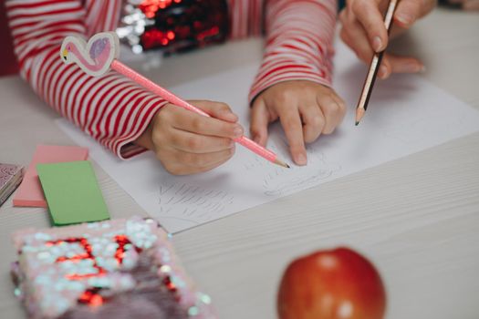 Distance learning online education. Mom does homework with her daughter at home. Distance learning online education. Hands of kid who is involved by drawing.