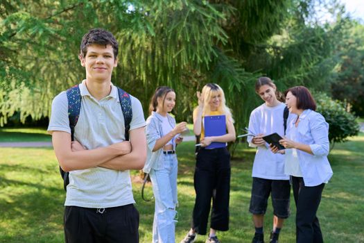 Portrait of male student in park campus, group of teenagers with teacher background. Adolescence, college, high school, education concept.