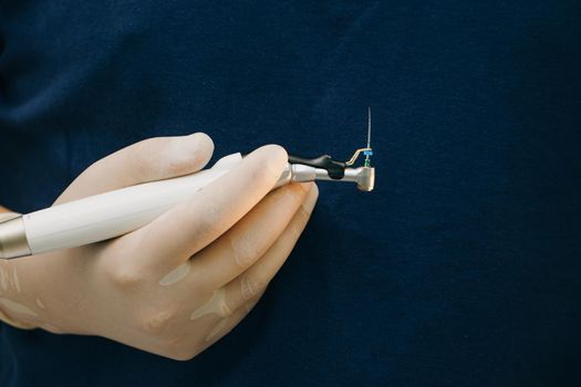 Close up of dentist hand with special tool for removing nerve from tooth. Dentist orthopedist tools. Surgical of instruments used in dental implantology.