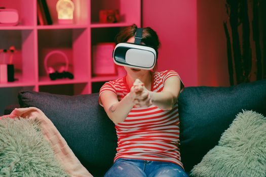 Woman playing and smiling in the VR headset. Virtual reality helmet on color lighting background