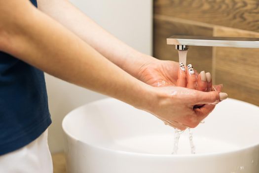 Wash hands with soap warm water rubbing fingers washing frequently or using hand sanitizer gel. Coronavirus pandemic prevention. Hands of woman wash their hands in a sink to wash the skin the hands.