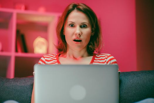 Surprised woman face looking at laptop screen. Close up of excited woman watch online news at computer. Portrait of happy girl shopping website at laptop