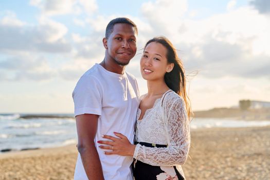 Loving romantic hugging young multiethnic couple on seashore. Happy african man and asian woman together. Love, relationship, dating, happiness, multicultural family, tourism, travel, people concept