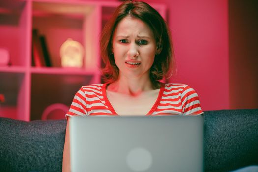 Shocked stressed young woman looking at laptop screen feeling bad surprise, amazed girl using computer reading shocking unbelievable online news writing technical support of pc problem sit at home