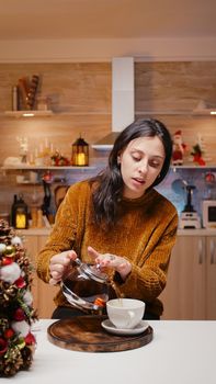 POV of festive woman using video call communication, talking to family and waving on christmas eve. Young adult looking at camera, chatting on online conference for remote holiday celebration.