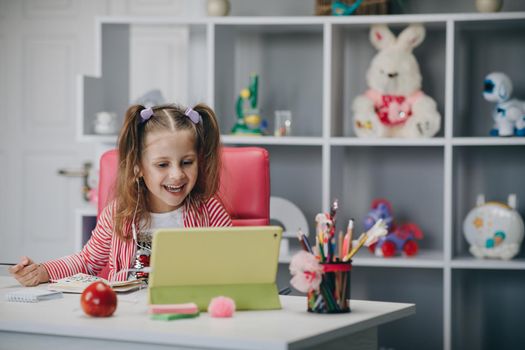 Concept learning at home. Girl video call online via the internet tutor on the tablet, child is study and greeting good morning teacher while sitting in the living room at home